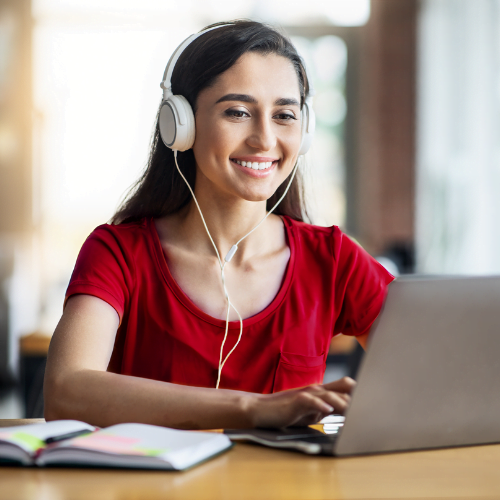 Woman with a headset on a laptop with a notebook to represent how Rosemont College Professional Studies are part of why Rosemont College is a Forbes Rated best online college and a best mainline college.
