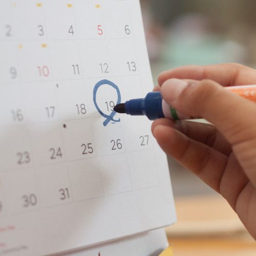 Close up of a hand circling a date on a calendar to represent how school calendars are part of why Rosemont College is Forbes rated best online college, and a best Main Line college.