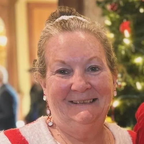 Close up of a smiling Lois Sauer with a Christmas tree in the background to represent how the Payroll Manager is part of why Rosemont College is a Forbes rated best online college, and a best Main Line college.