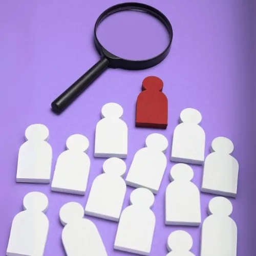 A magnifying glass and a bunch of people icons to represent how employees are part of why Rosemont College is a Forbes rated best online college, and a best Main Line college.