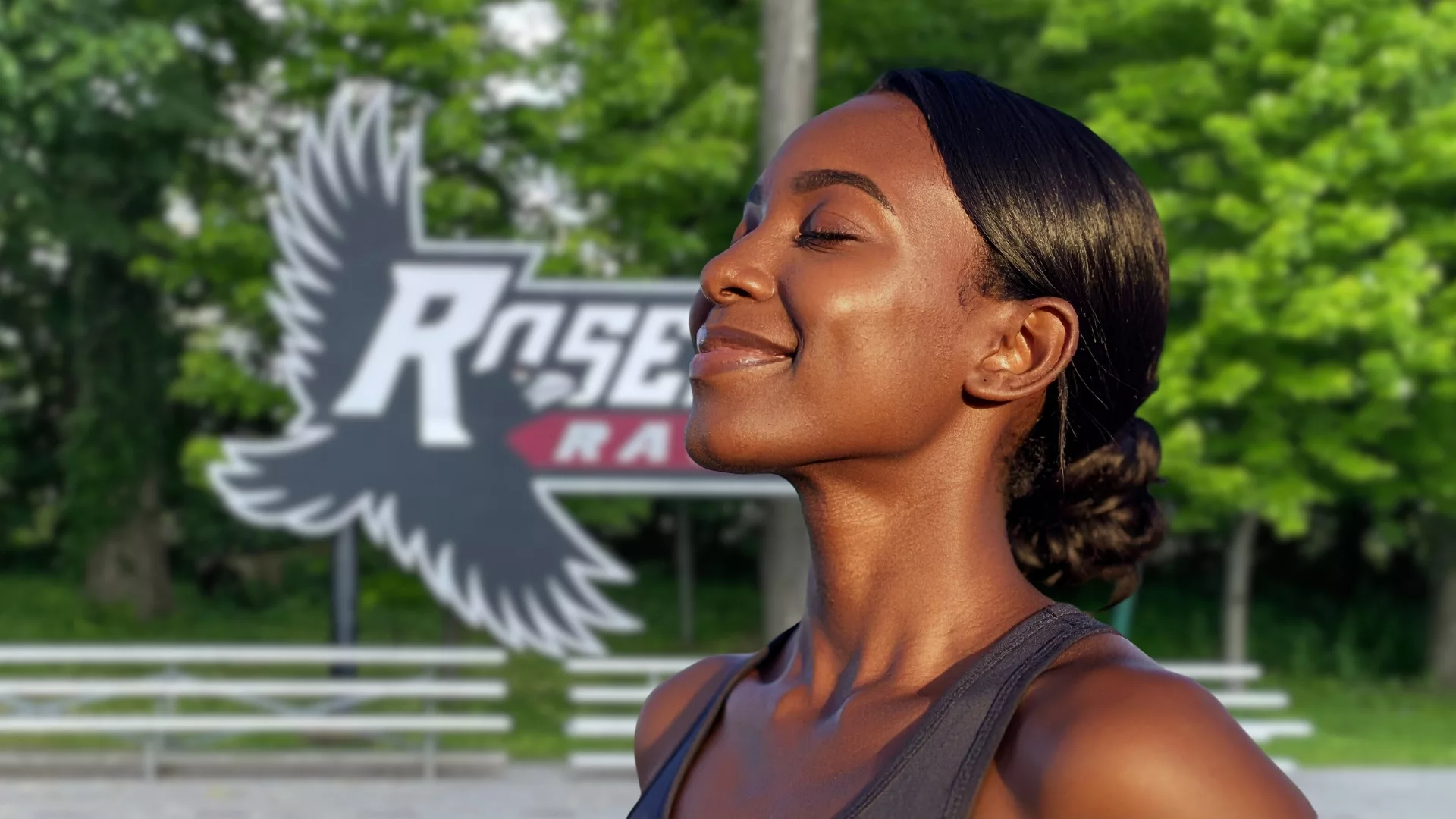 A close up of a woman taking a deep breath in front of the Ravens athletic complex to represent how wellness Wednesday is a part of why Rosemont College is a Forbes rated best online college, and a best Main Line college.
