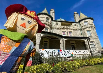 Scarecrow next to the main building Rathalla with a banner that reads Oktoberfest to represent how Rosemont College is a Forbes rated best online college, and a best Main Line college.