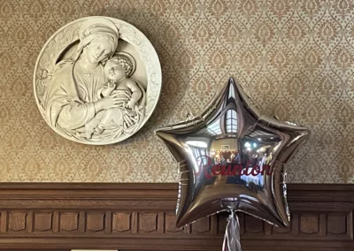 Reunion 2025 balloon next to artwork of Mary and Jesus to represent how Rosemont College is a Forbes rated best online college, and a best Main Line college.