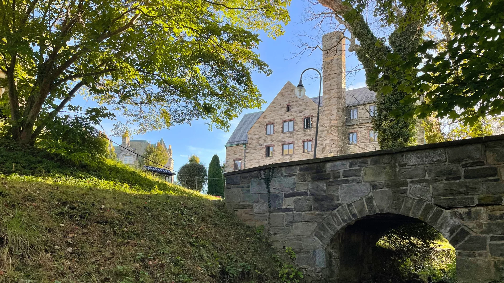 Rosemont College Campus - Mayfield Hall Stone bridge on campus with Mayfield Hall in the distance to represent how Rosemont College is a Forbes rated best online college, and a best Main Line college.