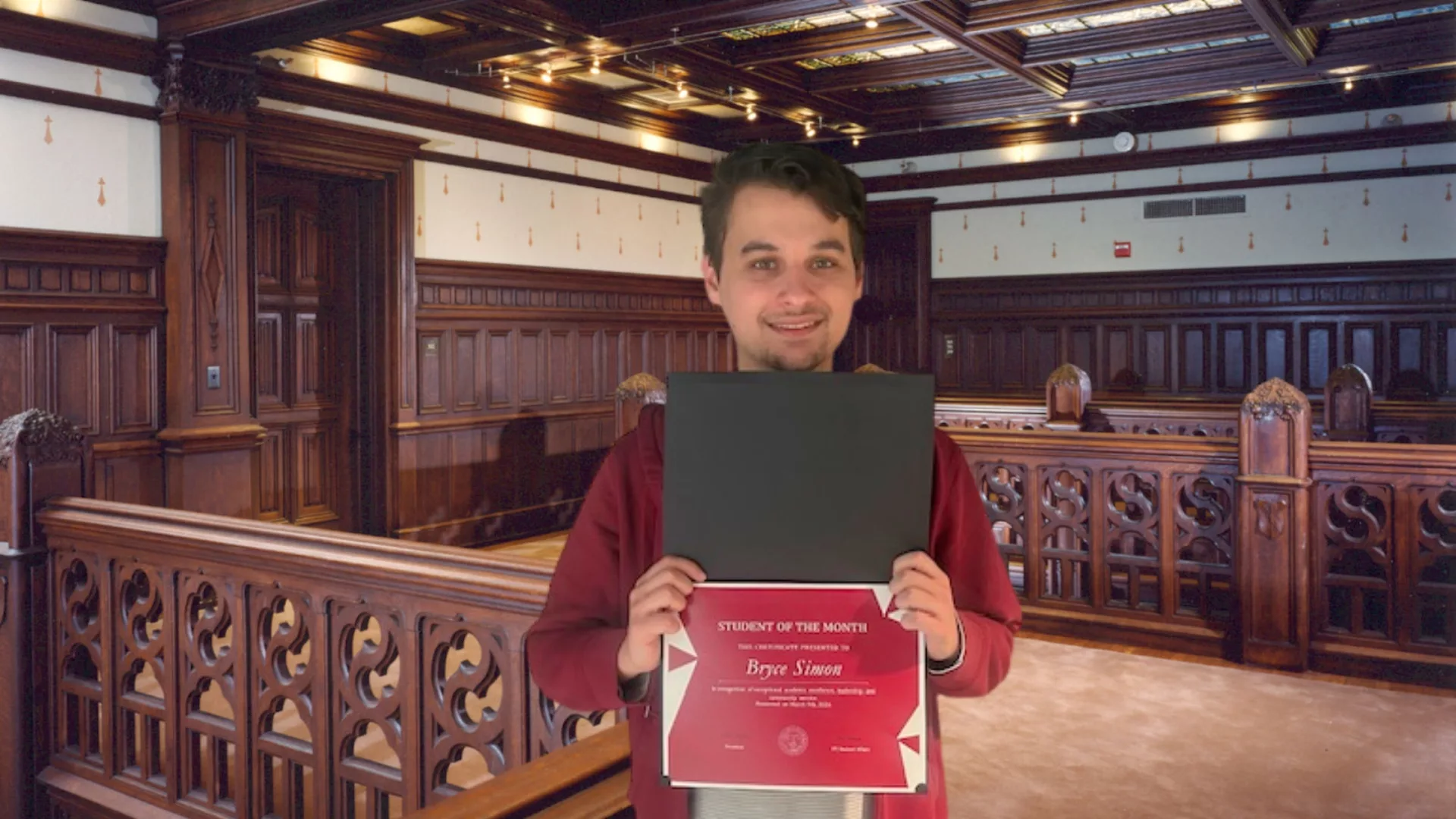 Bryce Simon holding his February Student of the Month certificate on the second floor of Main building to represent how Rosemont College is a Forbes rated best online college, and a best Main Line college.