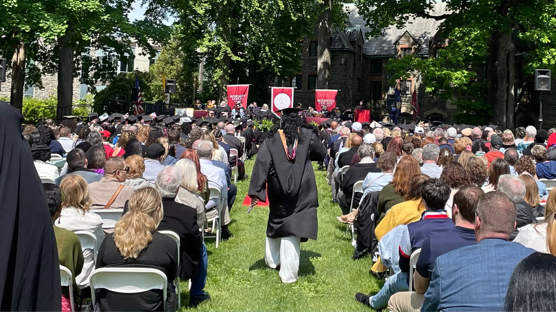 A 2026 graduate walking towards the stage at the Rosemont College 103rd Commencement to represent how graduation is a part of why Rosemont College is a Forbes rated best online college, and a best Main Line college.