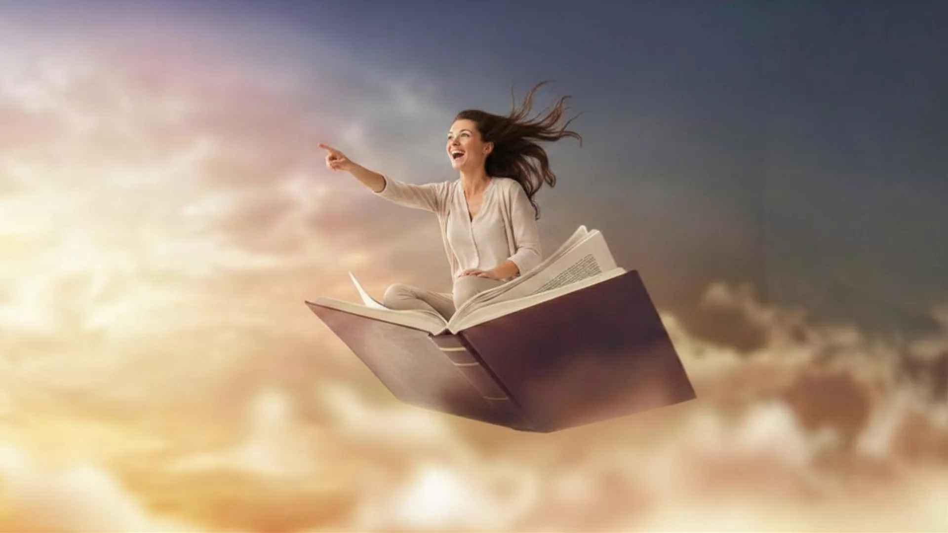 A smiling woman pointing and looking ahead while seated on a book as she appears to be flying through a beautiful sky to represent how the Weeklong Writer's Retreat- Short Story with Elise Juska is a part of why Rosemont College is a Forbes rated best online college, and a best Main Line college.